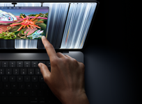 MacBook Pro med PROLED XDR-skjerm i fargen stellarsvart, brukeren justerer størrelsen på et vindu på skjermen med fingeren.