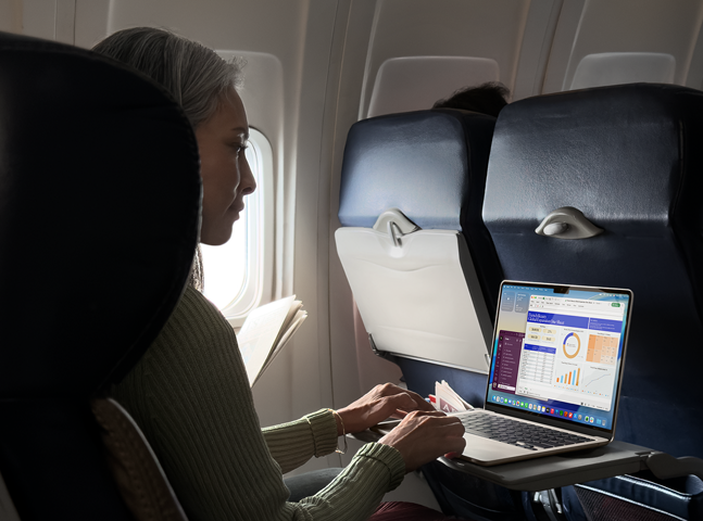 En person bruker en MacBook Air om bord i et fly for å vise Macens lange batteritid